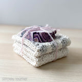 two crochet dishcloths folded and stacked with a bar of soap on the top