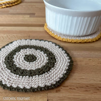 2 round crochet hot pads one with a dish sitting on it 