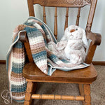 close up of a stuffed rabbit and a striped waffle stitch crochet baby blanket striped