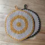 2 crochet round trivets laying flat one mostly on top of the other