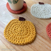 yellow crochet pumpkin coaster with other coasters in the background