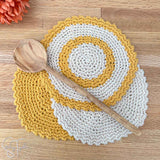 round crochet dishcloths stacked on each other with a wooden spoon laying on top of them