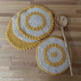 3 round crochet dishcloths and a matching round crochet trivet on a counter with a wooden spoon