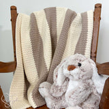 suzette stitch crochet blanket draped on a small rocking chair with a stuff bunny on the seat