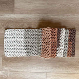 crochet v stitch scarf folded on itself on the floor in a way where you can see all the color blocks of the scarf