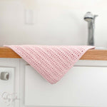 pink crochet dishcloth hanging on edge of counter