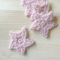 pink fuzzy crochet stars laying on a desk