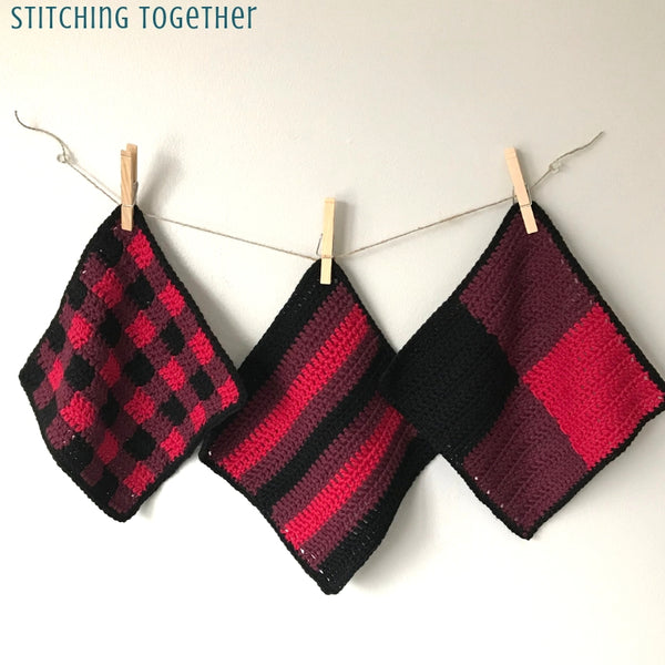 three red, wine and black dishcloths hanging on clothes pins
