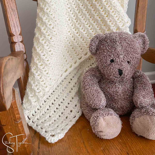 crochet baby blanket and stuffed bear on small rocking chair