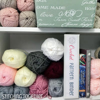 shelves full of yarn with a crochet pattern binder and crochet books