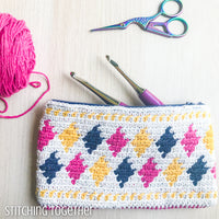 colorful crochet pouch staged with crochet hooks, yarn and scissors