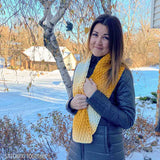 woman wearing a winter coat while holding a crochet scarf that's around her neck