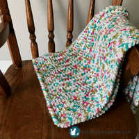 folded squishy crochet baby blanket on arm of rocking chair