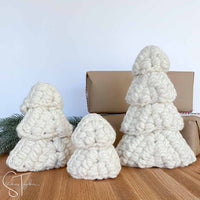 3 white crochet Christmas trees in front of presents