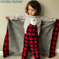 gray and buffalo plaid baby blanket being held by girl