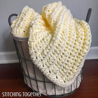 yellow crochet baby blanket in a basket
