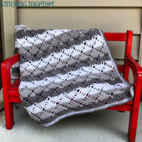 gray and white crochet blanket draped on red bench