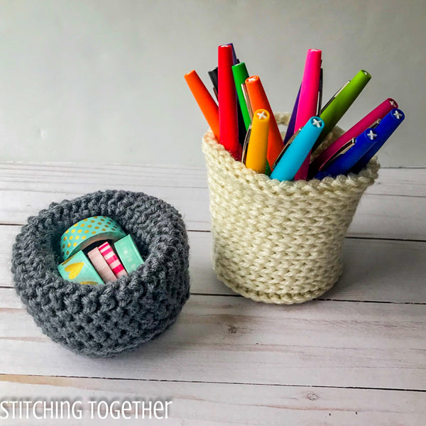 two crochet baskets filled with pens and tape