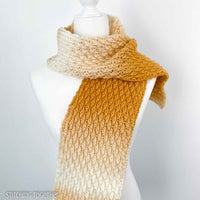 white and yellow crochet scarf around the neck of a mannequin