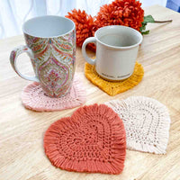two mugs sitting on heart crochet coasters with 2 other coasters laying in from of the mugs