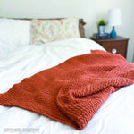 orange crochet blanket draped on the end of a bed