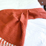 terracotta crochet lap blanket draped on the end of a bed