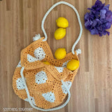 crochet market bag filled with lemons spilling out resting on a counter