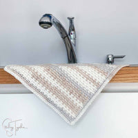crochet moss stitch dishcloth draped over the edge of a counter