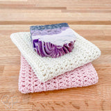 stack of two dishcloths crocheted with a bar of soap on top