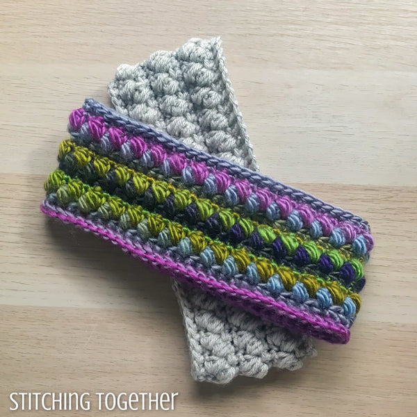 a colorful crochet ear warmer on top of a neutral ear warmer