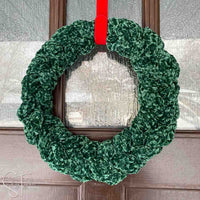 green crochet wreath hanging on a front door