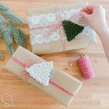 wrapped christmas presents with crochet trees and twine around them