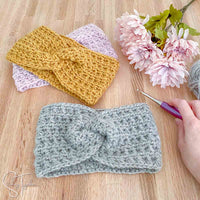 twisted crochet ear warmers, flowers, a hand holding a crochet hook and yarn