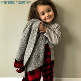 girl hugging a crochet baby blanket with buffalo plaid borders