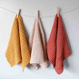 3 solid crochet hand towels hanging from clothes pins 