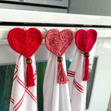 3 crochet hearts on dishtowels hanging on an oven bar