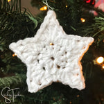 white crochet star christmas ornaments hanging on a tree