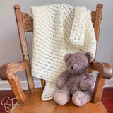 lacy crochet baby blanket and stuffed bear on small rocking chair