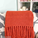 orange crochet lap blanket draped on a chair