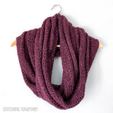 large crochet infinity scarf draped on a hanger