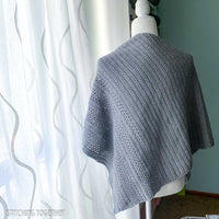 back of a gray crochet shawl on a mannequin