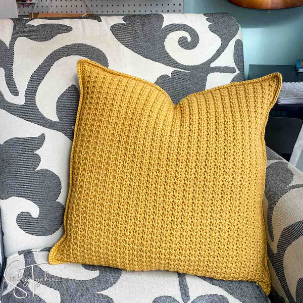 yellow crochet pillow sitting on a chair