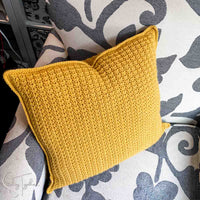 textured crochet pillow sitting on a chair