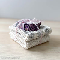two crochet dishcloths folded and stacked with a bar of soap on the top